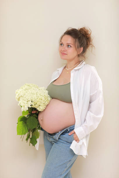 healthy pregnancy. side view pregnant woman with big belly advanced pregnancy in hands. girl holding big bouquet of flower. copy space for text. elegant mother waiting baby. selective focus. - mothers day mother single flower family stock-fotos und bilder