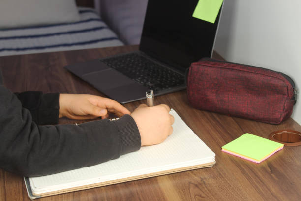 istock Distance learning online education. A schoolboy boy studies at home and does school homework. Student trying to write a composition. Stay at home concept idea. 2025431033