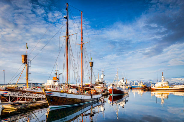 13 April 2018: Husavik, Iceland. The harbour at Husavik in Northern Iceland, with whale-watching vessels reflected in the calm water.
