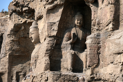 View of the 13.7-meter-tall colossal Buddha of Cave 20, an icon of Chinese art, excavated from the sandstone cliff at Yungang Grottoes, ancient Chinese Buddhist temple grottoes built during the Northern Wei dynasty near the city of Datong, in the province of Shanxi. They are excellent examples of rock-cut architecture and one of the three most famous ancient Buddhist sculptural sites of China. The others are Longmen and Mogao.