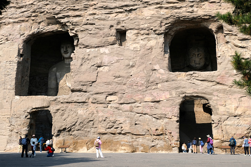 Tourists sightseeing the Yungang Grottoes, ancient Chinese Buddhist temple grottoes built during the Northern Wei dynasty near the city of Datong, in the province of Shanxi. They are excellent examples of rock-cut architecture and one of the three most famous ancient Buddhist sculptural sites of China. The others are Longmen and Mogao.