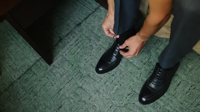 close-up of man hands tying laces on classic black leather shoes