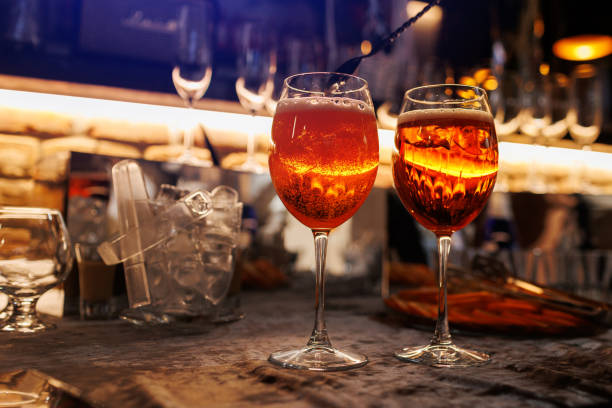 Two glasses of cocktail spritz on bar counter. Making typical alcoholic italian beverage, aperitif made with Prosecco sparkling white wine, ice and fresh orange slices. Mixing orange liquid. Two glasses of cocktail spritz on bar counter. Making typical alcoholic italian beverage, aperitif made with Prosecco sparkling white wine, ice and fresh orange slices. Mixing orange liquid crystal chalice stock pictures, royalty-free photos & images