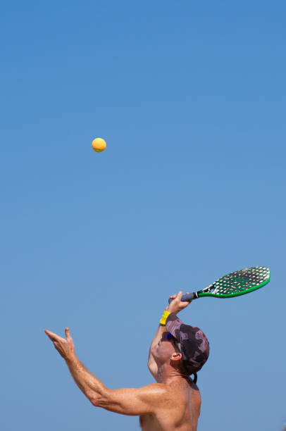 Man doing a beach tennis serve