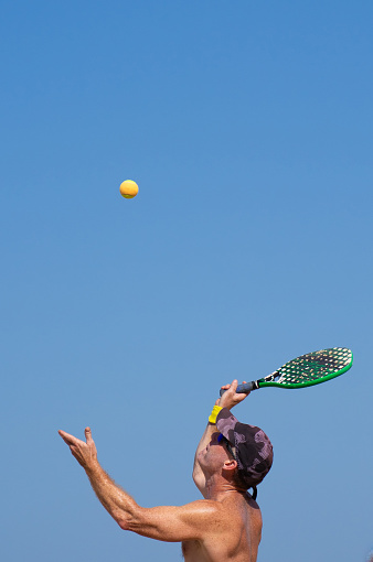 Man doing a beach tennis serve