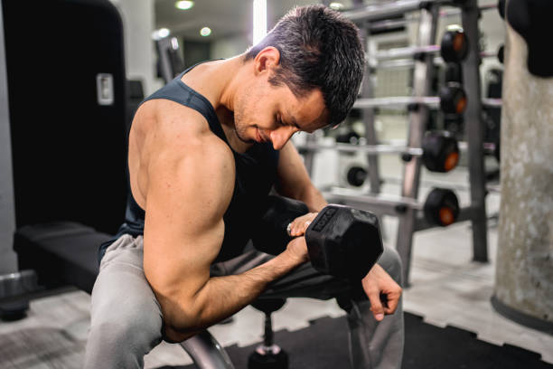 istock Strong muscular men in the gym doing biceps curl with dumbbell 2025522203
