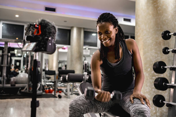 istock Black woman filming a tutorial in the gym while doing biceps curl with dumbbell 2025525439
