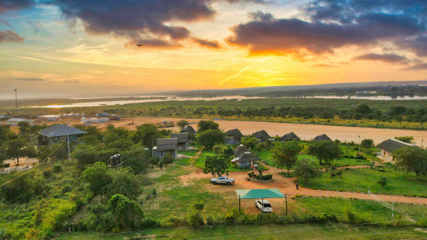 A tranquil river winds through the lush expanses of Kafue National Park, flanked by diverse vegetation and a clear sky, showcasing the natural beauty of Zambia's largest park.