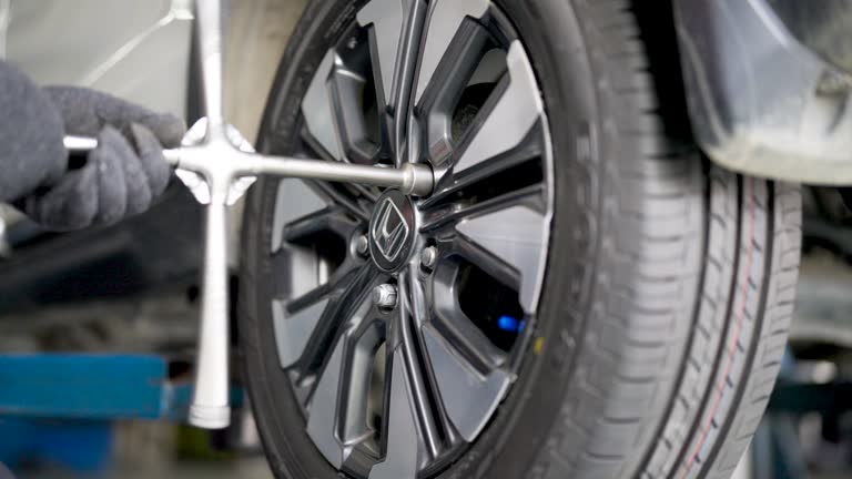 The car mechanic used a cross wrench to tighten the wheel nuts of the drilled wheels. Hole in tire. Changing the tire.