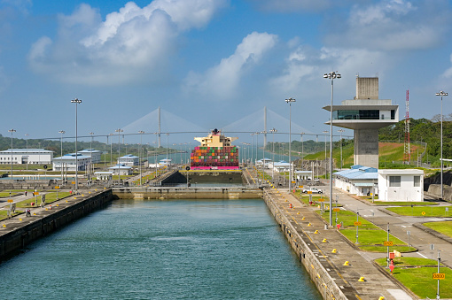 Colon, Panama - 23 January 2024: Agua Clara locks and control tower on the Panama canal. In the background is a container ship and the Atlantic bridge
