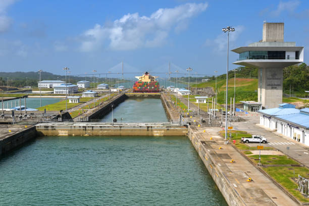 Colon, Panama - 23 January 2024: Agua Clara locks and control tower on the Panama canal. In the background is a container ship and the Atlantic bridge