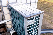 Outdoor unit of a low-power air heat pump located in front of the house.
