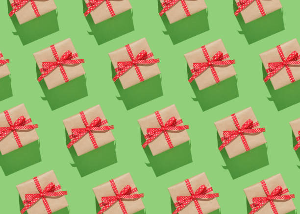 istock Pattern of brown gift boxes on with red bows on green background. 2025581513