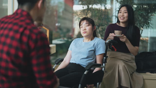 Social Gathering Asian Chinese cerebral palsy woman in wheelchair with friends in cafe weekend morning