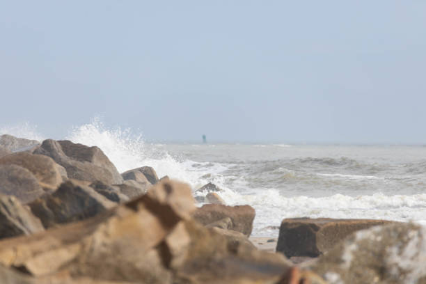 Large pile of rocks creating a breakwater on the beach with ocean in background
