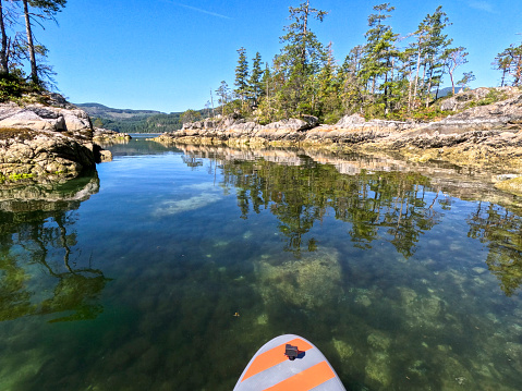 Aerial view of woman paddle boarding on ocean with mountains and dramatic sky