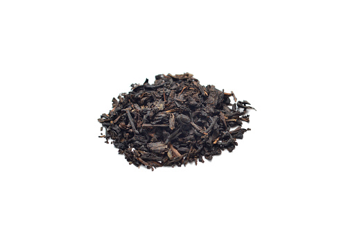 Closeup of a heap of black loose leaf tea on a white background.