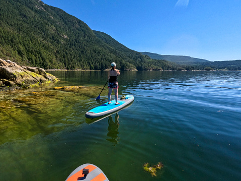 Aerial view of woman paddle boarding on ocean with mountains and dramatic sky