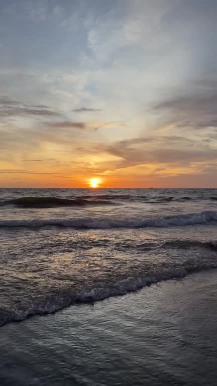 Sea surf against the backdrop of a picturesque bright orange sunset sun, Indonesia