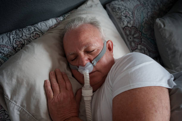 istock Mature Man Sleeping with a CPAP (Continuous positive airway pressure) Machine after being diagnosed with Sleep Apnea 2025683486