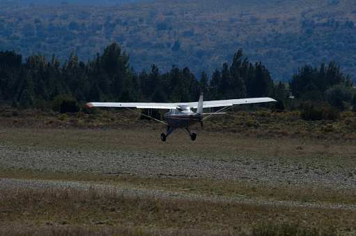 plane landing or taking off, light plane seen from behind with the propeller turning and mountains in the background