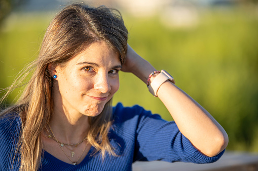 Woman looks confused while posing outdoors with the sun illuminating her face.