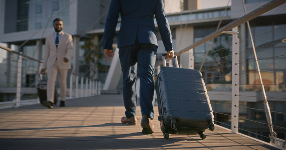 Business, person and travel with luggage outdoor at airport or walking to hotel at sunset. Suitcase, bag and professional businessman moving on sidewalk with journey on road in morning or city