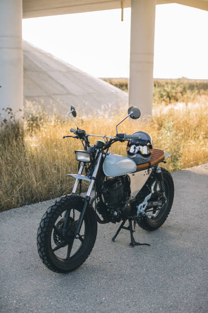 A stylish caferacer motorcycle stands on the road during sunset.
