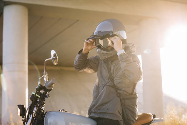 istock A biker puts on a helmet while sitting on a motorcycle.A man rides a motorcycle at sunset. 2025775820