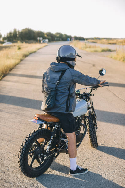 istock Biker on a cafe racer motorcycle on the road at sunset. Rear view. 2025776885