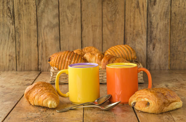 two mugs of coffee and hot croissants on a old wooden background