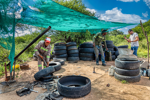 millennial african american workers ,working on the side of the road changing and fixing tires, air compressor in the foreground