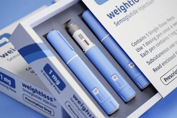 Photo of Two packages of 5 dosing pens each of a fictitious Semiglutin drug used for weight loss (antidiabetic medication or anti-obesity medication) on a blue transparent background. Fictitious package design