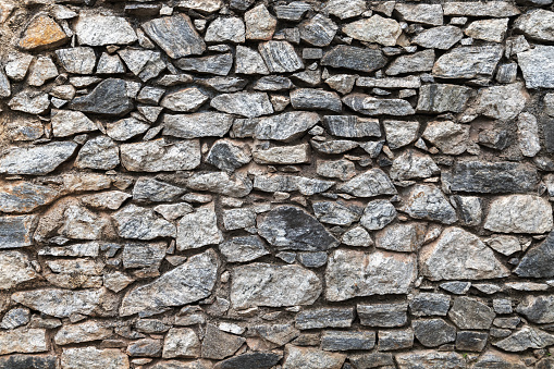 Old dark gray stone wall, background photo texture, front view