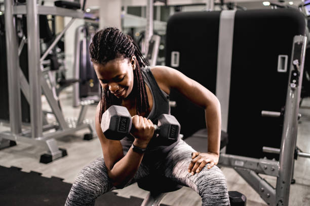 istock Black woman in the gym doing biceps curl with dumbbell 2025851958