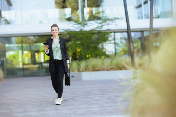 istock female worker in business district using smartphone and walking 2025859859