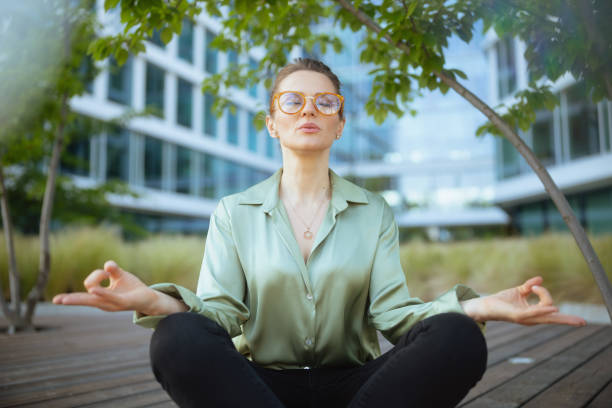 relaxed woman worker in green blouse and eyeglasses meditating - last opportunity emotional stress green stock-fotos und bilder