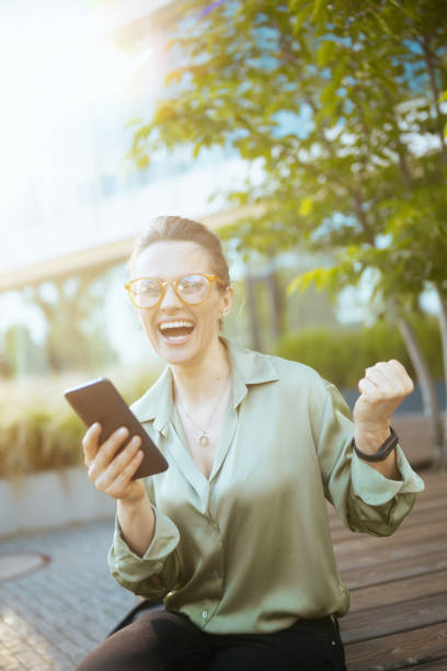 istock woman employee in green blouse using phone and rejoicing 2025859873