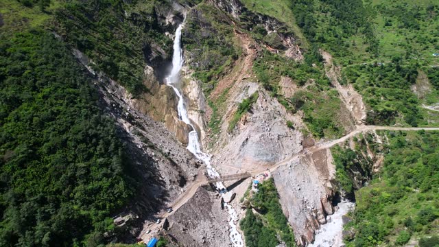 Rupse Falls And Off-road SUV Cars Drive on Steep Rough Mountain Dirt Road in Central Nepal During Summer Day - Aerial Pull Back Reveal