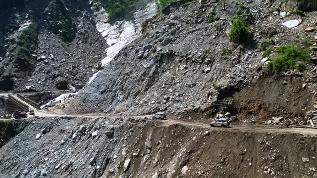 Off-Road Jeeps Drive on Steep Narrow Mountain Dirt Road Passing Rupse Falls in Central Nepal - Aerial Panning