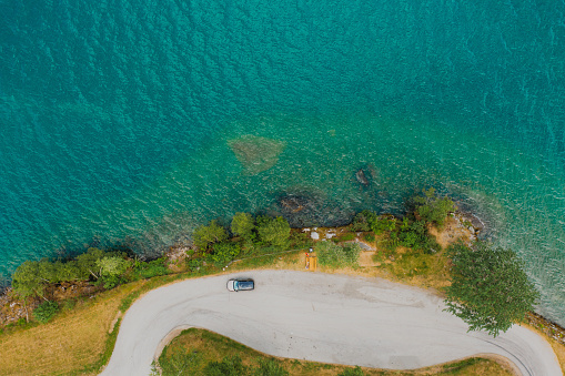 Drone high-angle photo of car on unbelievable free parking lot surrounded by green pine forest and turquoise fjord in Jostedalbreen National Park, Western Norway, Scandinavia