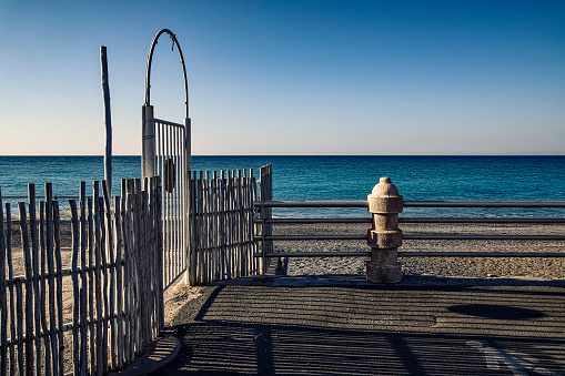 a white wooden gate  near the deserted beach  of  Bordighera in Italy
