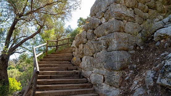 Stone wall and wooden staircase in ancient city Amos near town or village of Turunc, Turkey. It was located in Rhodian Peraia in Caria on Mediterranean coast.