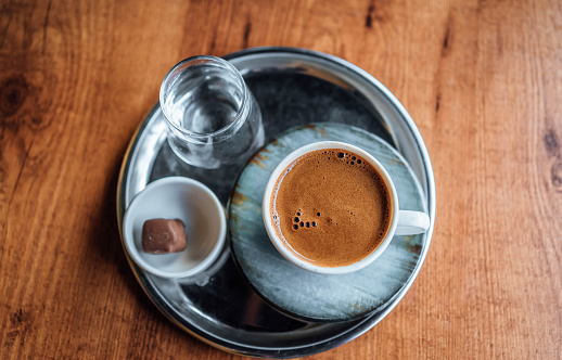 Cup of hot black traditional Turkish coffee served with glasses of water on a tray