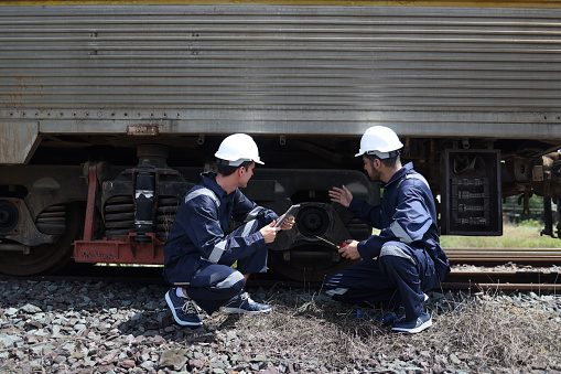 Maintenance and technician railway checking the power train of oil cargo train and the railway work on railroad station with the tablet.