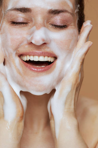 istock smiling young female with foaming face wash washing face 2025971841