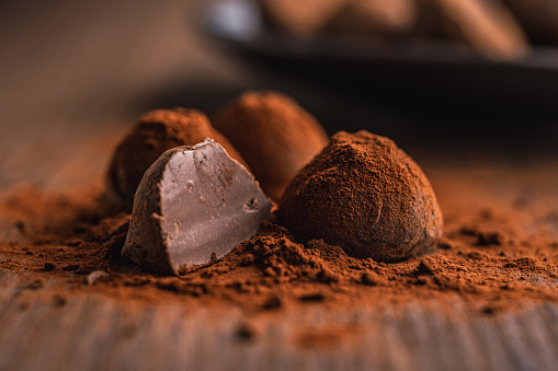 Chocolate truffles covered with cocoa powder on wooden table.