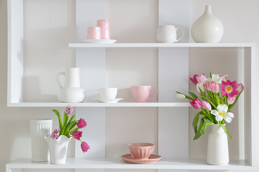 tulips in vase on white shelf with kitchenware