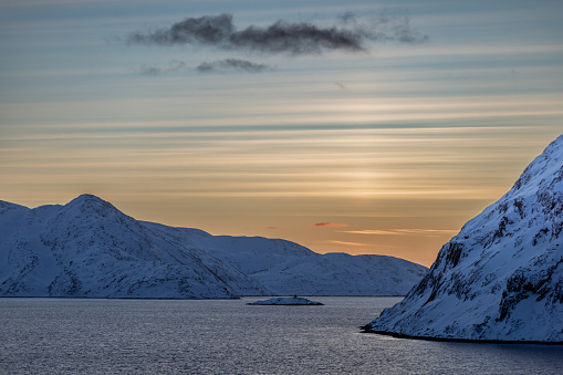 Sun is setting on fjord.\nHammerfest - Norway
