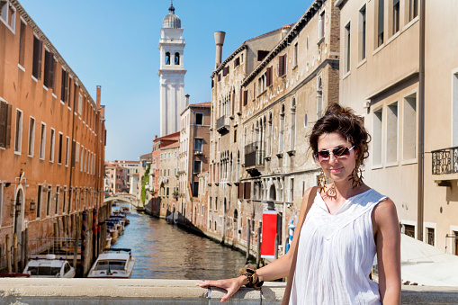 Beautiful woman enjoys the view to a canal in Venice